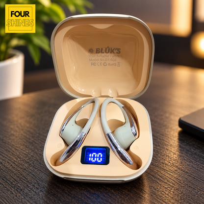 A pair of BLÜKS wireless earbuds resting inside an open beige charging case on a dark wooden table. The case has a small blue digital display showing '100' and the brand name 'BLÜKS' is printed inside the lid.