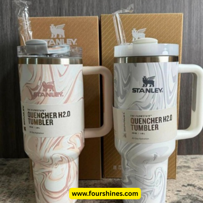 Two Stanley Quencher H2.0 tumblers with marbled designs on a wooden surface.
