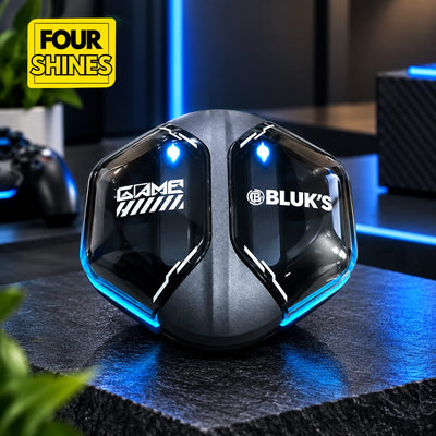 A black gaming accessory with glowing blue LED accents and white logos reading 'GAME' and 'BLUK'S' sits on a dark tabletop in a dimly lit room. A yellow 'FOUR SHINES' badge appears in the top-left corner.