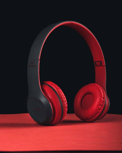 A pair of red P47 wireless Bluetooth headphones displayed next to its packaging box and a USB charging cable.