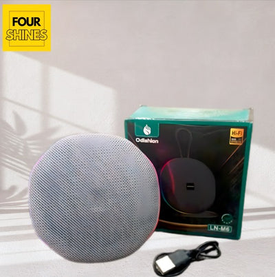 Round gray speaker with a black cable on a white surface, featuring the 'Four Shines' brand.