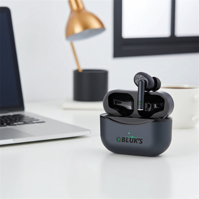 Black wireless earbuds in a charging case on a desk with a laptop and lamp in the background.