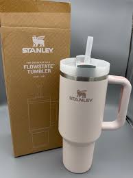 Stanley tumbler with handle and straw lid on a gray surface with Stanley packaging.