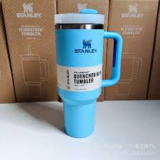 Blue Stanley tumbler with handle on a light gray background