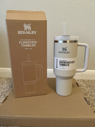 Stanley tumbler with straw and packaging on a cardboard surface.